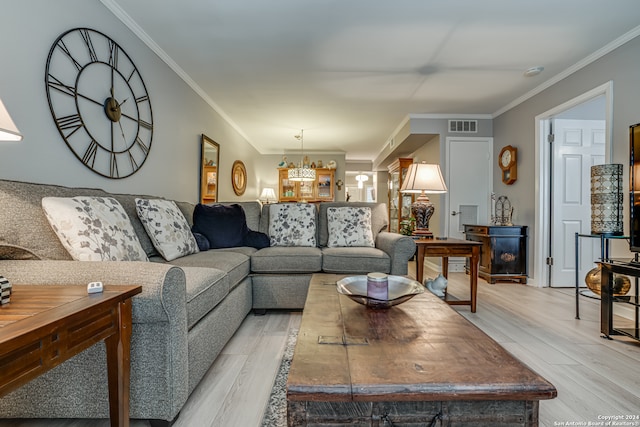 living room featuring a chandelier, ornamental molding, and light hardwood / wood-style flooring