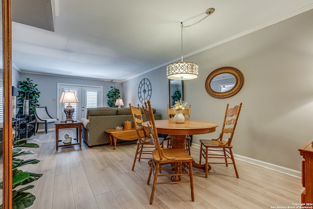 dining space with light hardwood / wood-style floors, ornamental molding, and french doors