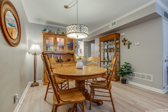 dining room with light wood-type flooring and ornamental molding