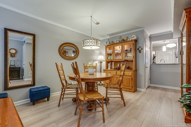 dining space featuring ornamental molding and light hardwood / wood-style flooring