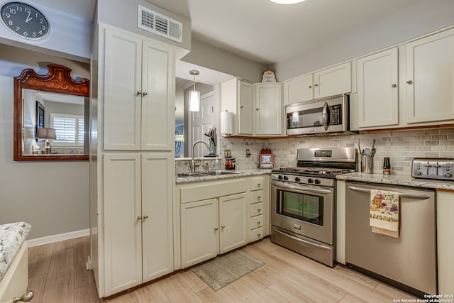 kitchen with backsplash, light hardwood / wood-style floors, sink, and appliances with stainless steel finishes