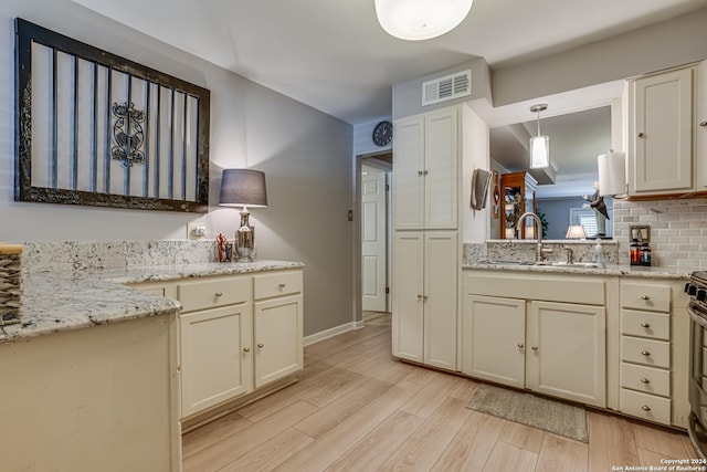 8058 Broadway Unit 147U, San Antonio, TX 78209 - kitchen featuring a sink, light wood-style floors, decorative backsplash, light stone countertops, and hanging light fixtures