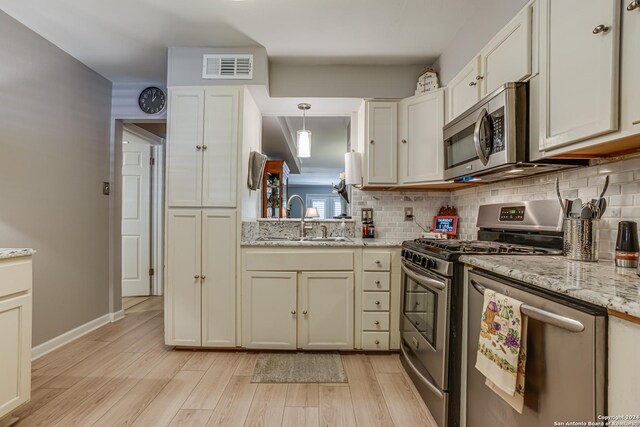 8058 Broadway Unit 147U, San Antonio, TX 78209 - kitchen featuring appliances with stainless steel finishes, a sink, light wood-type flooring, and backsplash