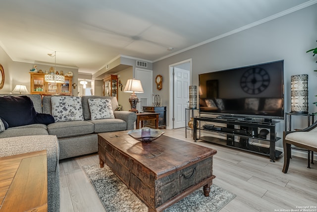 living room featuring a chandelier, crown molding, and light hardwood / wood-style floors