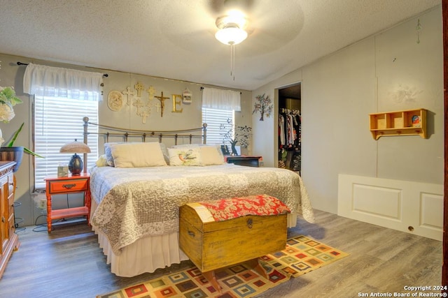 bedroom with lofted ceiling, hardwood / wood-style flooring, a spacious closet, a textured ceiling, and a closet