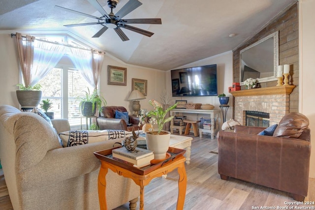 living room featuring lofted ceiling, a brick fireplace, ceiling fan, ornamental molding, and light hardwood / wood-style floors