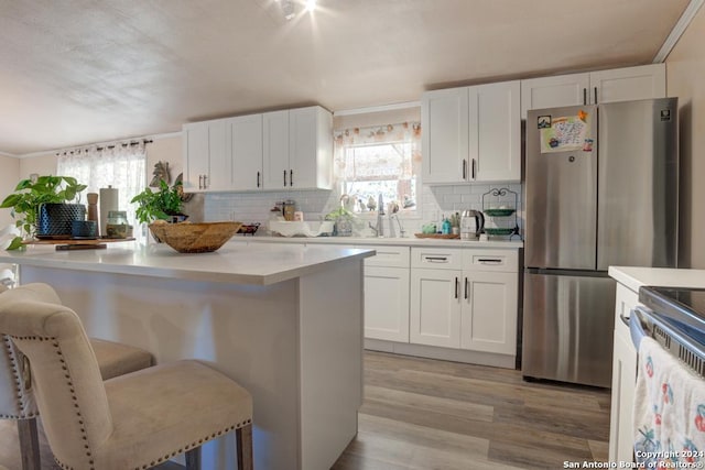 kitchen featuring a breakfast bar area, a kitchen island, white cabinets, and light wood-type flooring