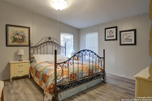 bedroom featuring a textured ceiling, hardwood / wood-style floors, and lofted ceiling