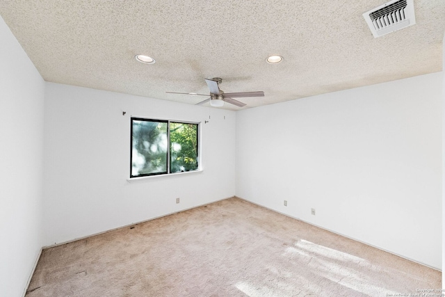 spare room featuring light carpet, a textured ceiling, and ceiling fan