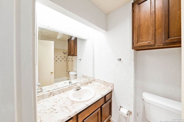 bathroom with vanity, toilet, and a textured ceiling