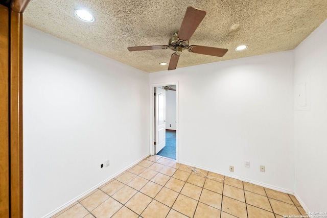 empty room with a textured ceiling, ceiling fan, and light tile patterned flooring