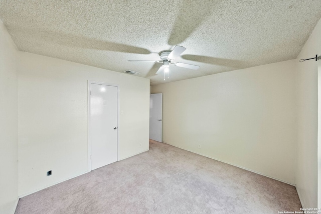 unfurnished bedroom with ceiling fan, light carpet, and a textured ceiling