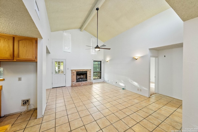 unfurnished living room featuring high vaulted ceiling, a brick fireplace, a textured ceiling, beamed ceiling, and light tile patterned flooring