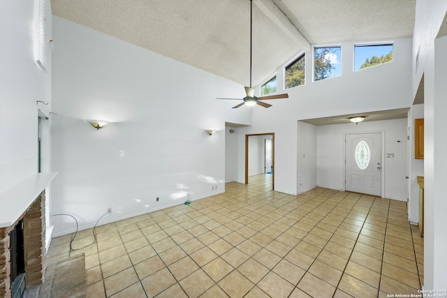 tiled entryway with beamed ceiling, a textured ceiling, high vaulted ceiling, and a healthy amount of sunlight