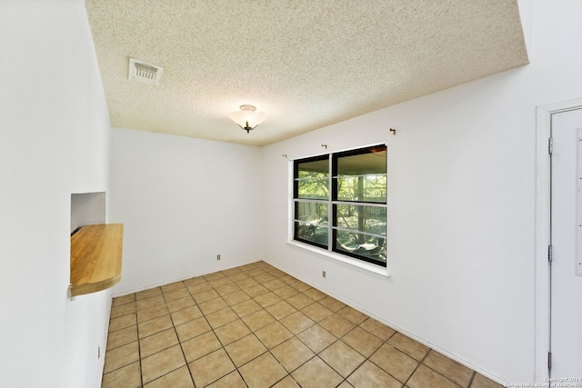 tiled empty room with a textured ceiling