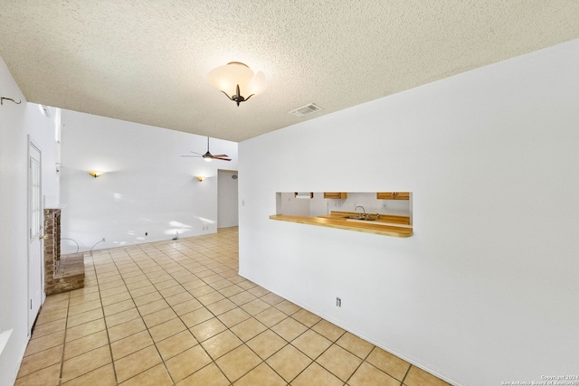 tiled spare room with ceiling fan, sink, and a textured ceiling