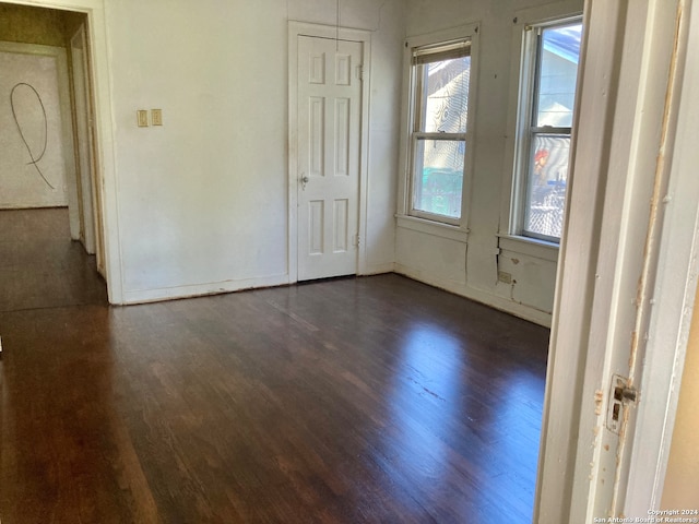 unfurnished room featuring plenty of natural light and dark wood-type flooring