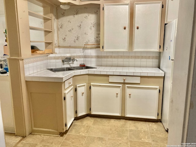 kitchen with cream cabinets, backsplash, tile countertops, and sink