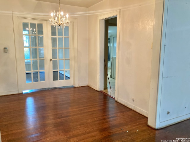 unfurnished dining area with french doors, dark hardwood / wood-style floors, and an inviting chandelier