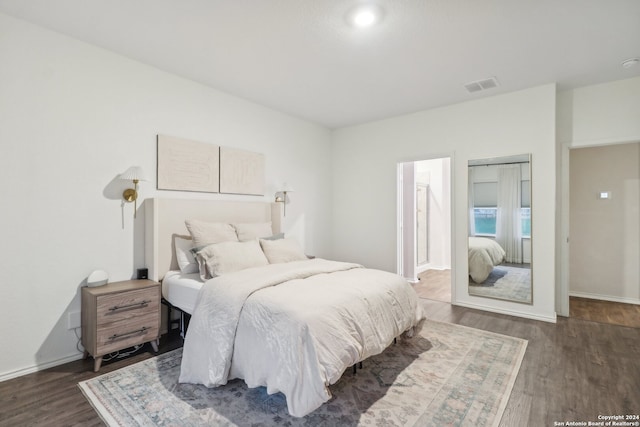 bedroom with connected bathroom and dark wood-type flooring