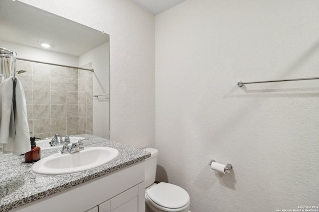 bathroom featuring vanity, toilet, and a tile shower