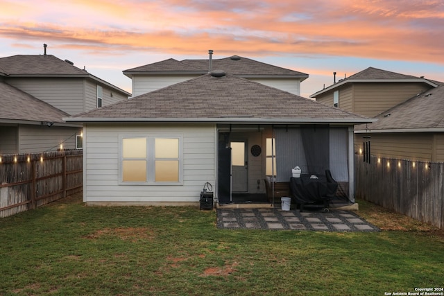 back house at dusk with a lawn