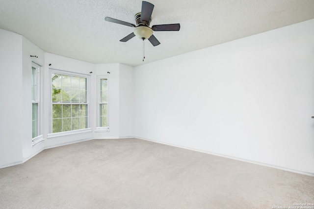 carpeted spare room featuring ceiling fan and a textured ceiling