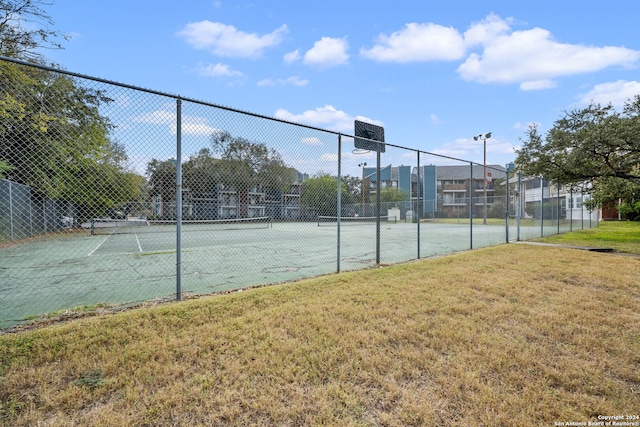 view of tennis court featuring basketball court and a lawn