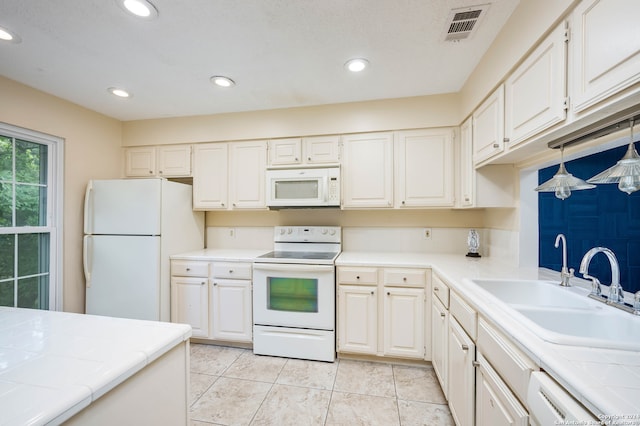 kitchen with white cabinetry, tile counters, white appliances, and sink