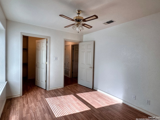 unfurnished bedroom with hardwood / wood-style flooring, a spacious closet, and ceiling fan