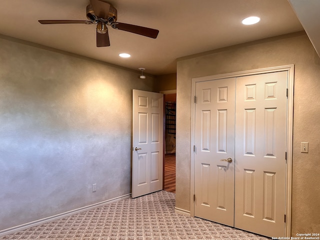 unfurnished bedroom featuring light carpet, a closet, and ceiling fan