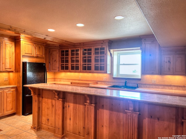 kitchen with a kitchen breakfast bar, black fridge, sink, and a textured ceiling