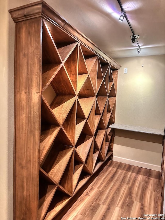 wine cellar with hardwood / wood-style flooring and track lighting