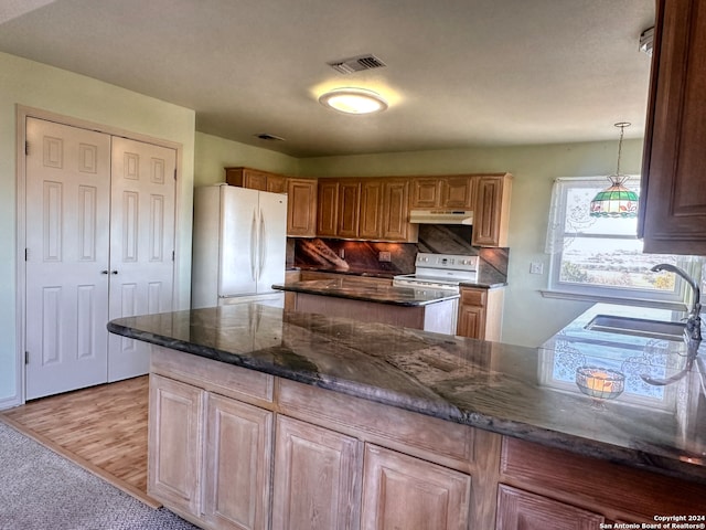 kitchen with decorative backsplash, dark stone counters, white appliances, sink, and light hardwood / wood-style floors