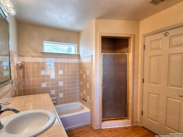 bathroom featuring vanity, wood-type flooring, a textured ceiling, and shower with separate bathtub