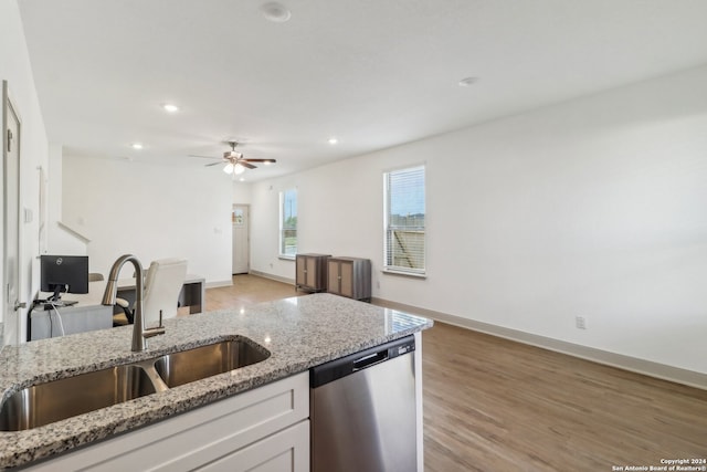 kitchen featuring light stone countertops, stainless steel dishwasher, sink, light hardwood / wood-style flooring, and white cabinets