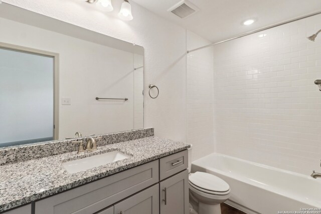 full bathroom with tiled shower / bath, vanity, and toilet