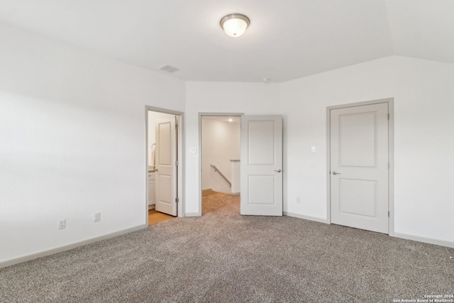 unfurnished bedroom with connected bathroom, light colored carpet, and vaulted ceiling