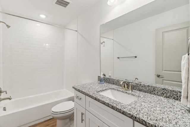 full bathroom featuring hardwood / wood-style floors, vanity, toilet, and tiled shower / bath combo