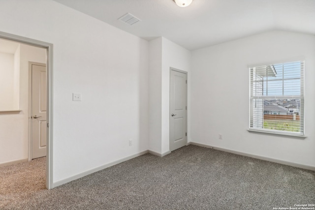 spare room with carpet and vaulted ceiling