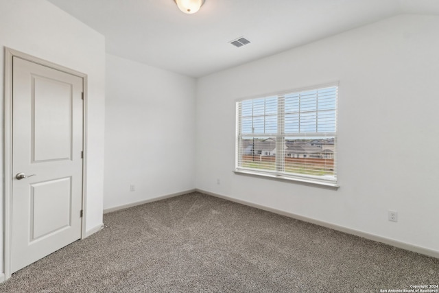 spare room featuring carpet flooring and lofted ceiling