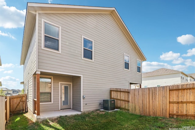 rear view of house featuring a lawn and central AC unit