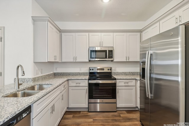 kitchen with sink, dark hardwood / wood-style floors, light stone countertops, appliances with stainless steel finishes, and white cabinetry