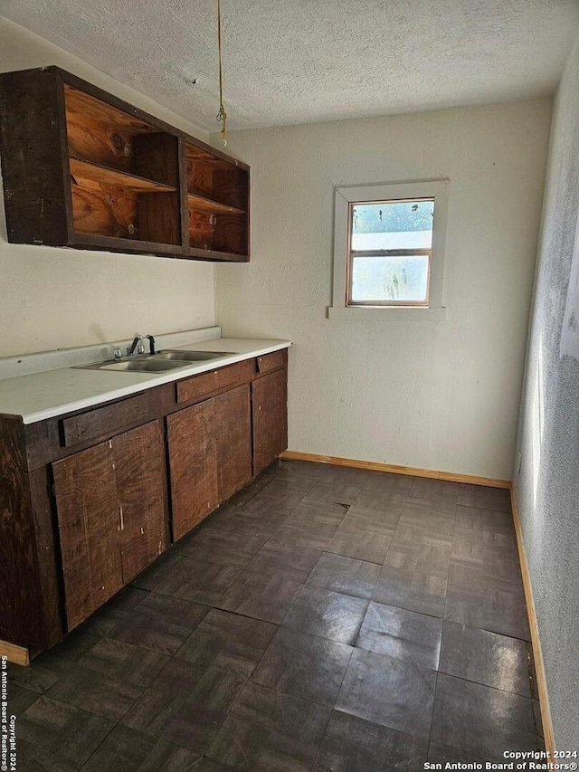 kitchen featuring sink, a textured ceiling, and dark brown cabinetry