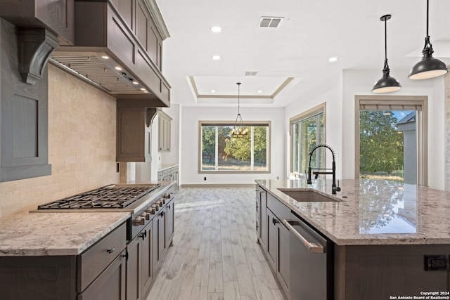 kitchen with pendant lighting, sink, light hardwood / wood-style flooring, light stone countertops, and extractor fan