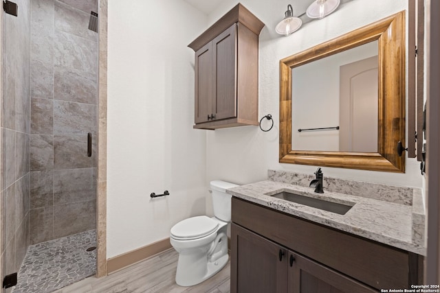 bathroom with tiled shower, vanity, hardwood / wood-style flooring, and toilet