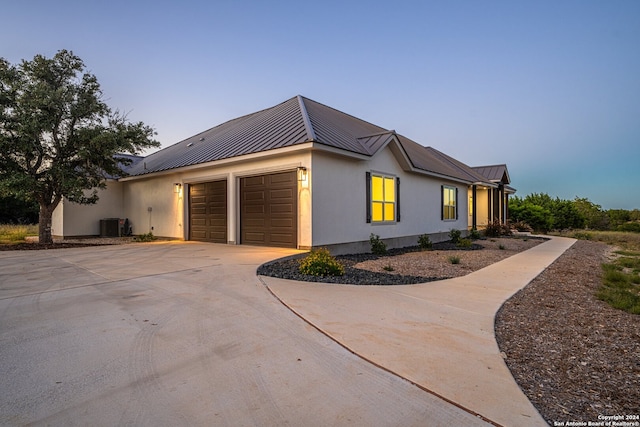 property exterior at dusk with central AC unit and a garage