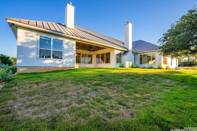 back of house featuring a lawn and ceiling fan