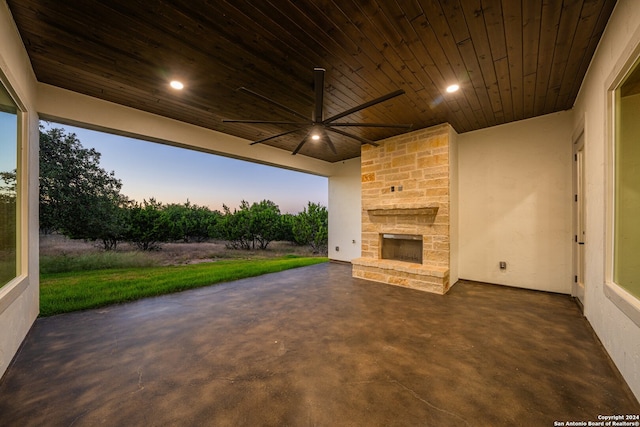 patio terrace at dusk featuring an outdoor stone fireplace and ceiling fan