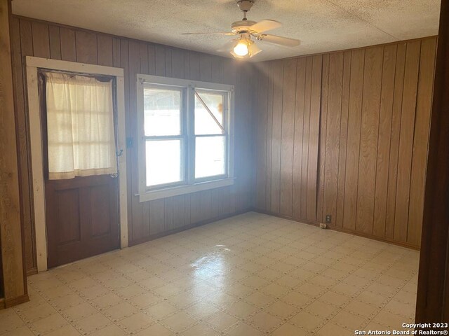17770 Interstate 35, Lytle, TX 78052 - spare room featuring light flooring, a ceiling fan, wood walls, and a textured ceiling
